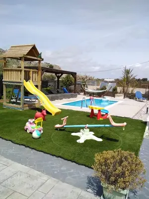 a backyard with a playground with a slide and a pool at Stergios villa in Kolimbia