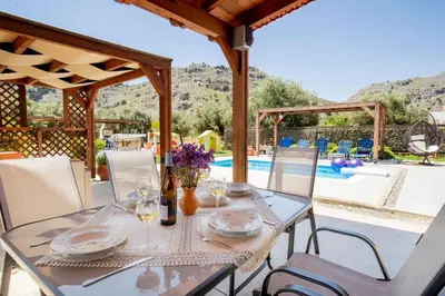 a table and chairs with a table and a pool at Stergios villa in Kolimbia