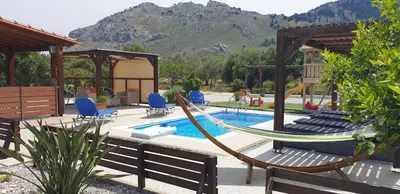 a patio with a hammock and a swimming pool at Stergios villa in Kolimbia
