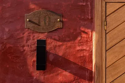 a wooden door with a sign on a red wall at 10GR Boutique Hotel & Wine Bar in Rhodes Town