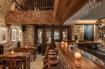 a restaurant with a bar with wooden tables and chairs at 10GR Boutique Hotel & Wine Bar in Rhodes Town