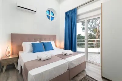 a bedroom with a large bed with blue pillows at Monte Smith Luxury Villas in Rhodes Town