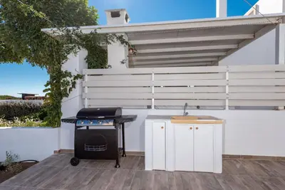 a barbecue grill on a patio with a white wall at Gennadi Villa Mary in Gennadi