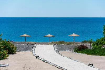 a walkway with umbrellas on a beach next to the ocean at Gennadi Villa Mary in Gennadi