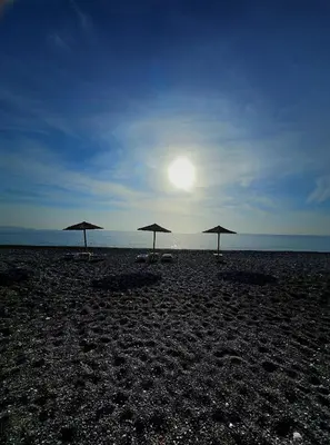 three umbrellas on a beach with the sun in the sky at Gennadi Villa Mary in Gennadi