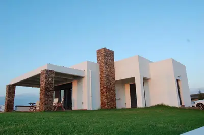 a white house with two towers on a grass field at CRISTELIA SEAFRONT & POOL VILLA in Lachania