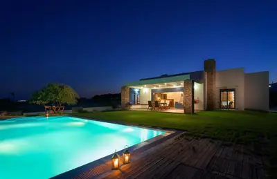 a villa with a swimming pool at night at CRISTELIA SEAFRONT & POOL VILLA in Lachania