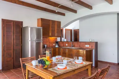 a kitchen with a wooden table and a refrigerator at CRISTELIA SEAFRONT & POOL VILLA in Lachania