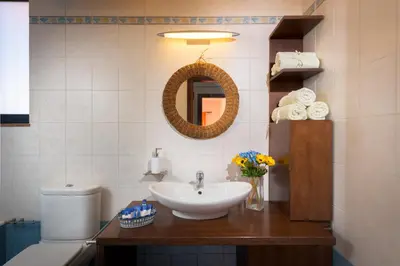 a bathroom with a sink and a toilet and a mirror at CRISTELIA SEAFRONT & POOL VILLA in Lachania