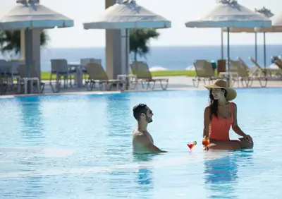 a man and a woman sitting in a swimming pool at Apollo Blue in Faliraki