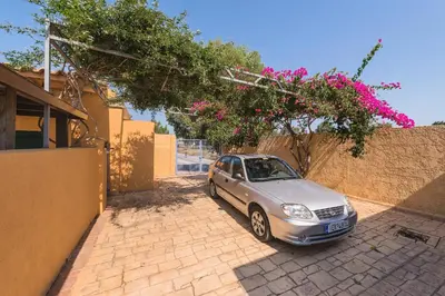 a small car parked next to a building with pink flowers at Eleftherias Garden House in Afantou