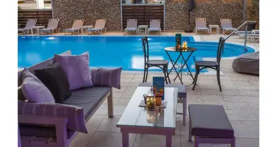 a couch and tables in front of a swimming pool at Majestic Hotel - Adults Only in Rhodes Town