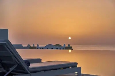 a view of the ocean with a beach chair and the moon at Lindos Grand Resort & Spa - Adults Only in Líndos