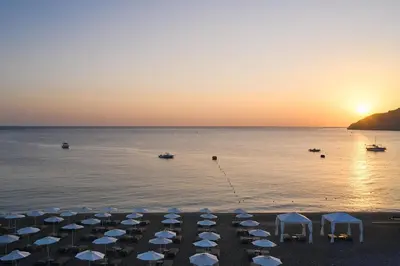 a group of umbrellas on the beach at sunset at Lindos Grand Resort & Spa - Adults Only in Líndos