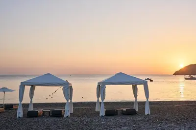 two white tents on the beach at sunset at Lindos Grand Resort & Spa - Adults Only in Líndos