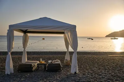 a tent on the beach with chairs and a table at Lindos Grand Resort & Spa - Adults Only in Líndos