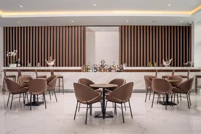 a bar in a hotel lobby with chairs and tables at Lindos Grand Resort & Spa - Adults Only in Líndos