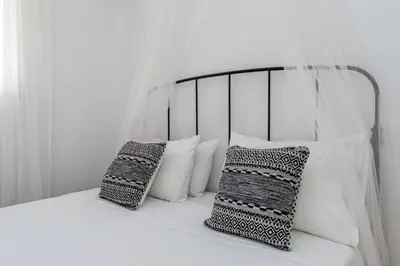 a bed with white pillows and a black and white canopy at Uno Luxury Apartment with Sea view in Livadia