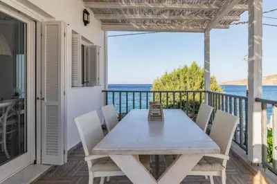 a wooden table and chairs on a balcony with the ocean at Uno Luxury Apartment with Sea view in Livadia