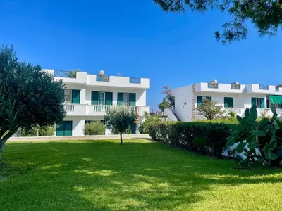 a white building with a green lawn in front of it at Villa Rizia in Kolimbia