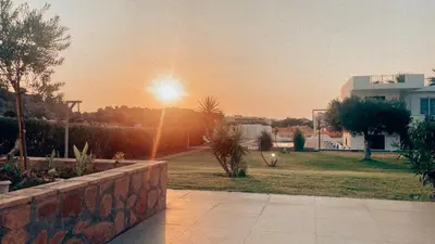 a sunset over a park with a building and a fence at Villa Rizia in Kolimbia
