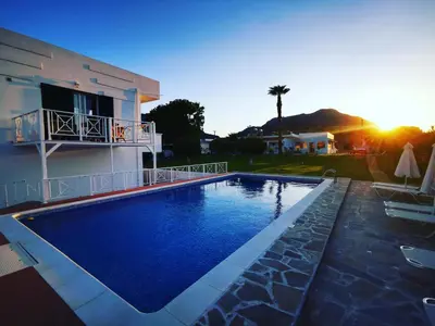 a swimming pool in front of a house with the sunset at Villa Rizia in Kolimbia