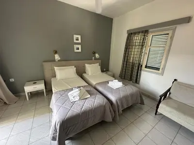 a bedroom with two beds and a couch and a window at George Apartments in Livadia