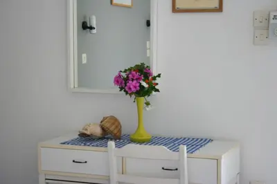 a vase of flowers on a table with a mirror at George Apartments in Livadia