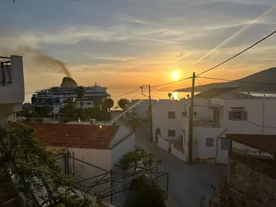 a cruise ship in the distance with buildings and the sunset at George Apartments in Livadia