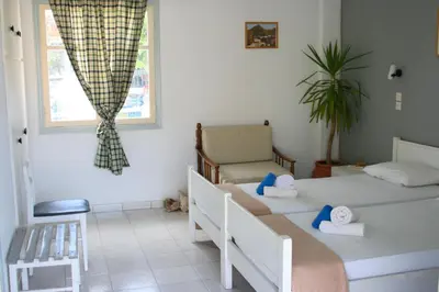a bedroom with two beds and a chair and a window at George Apartments in Livadia