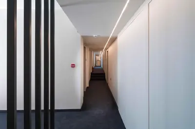 a corridor in a building with white walls and black floors at Mariette Rhodes Urban Suites in Rhodes Town