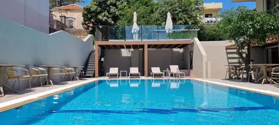 a swimming pool with chairs and a building at Mariette Rhodes Urban Suites in Rhodes Town