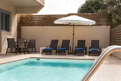 a pool with chairs and an umbrella next to a table and an umbrella at Villa Pandesia in Kremasti