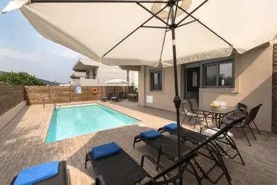 a patio with an umbrella and a swimming pool at Villa Pandesia in Kremasti
