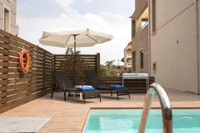 a patio with chairs and an umbrella next to a pool at Villa Pandesia in Kremasti
