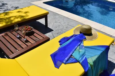 a yellow table with a hat next to a pool at Olive Sense Villa with jacuzzi and sauna in Afantou