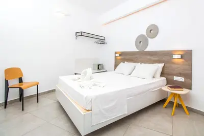 a bedroom with a large white bed and a chair at Hillside Studios & Apartments in Faliraki