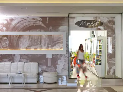 a woman walks past a martini store in a mall at Epsilon Hotel Apartments in Faliraki