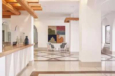 a living room with white walls and wooden ceilings at Epsilon Hotel Apartments in Faliraki