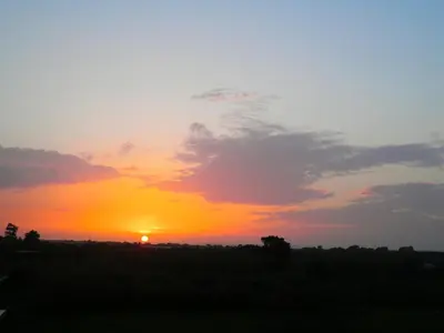 a sunset in a field with the sun in the sky at Alexia Apartments & Studios in Kremasti