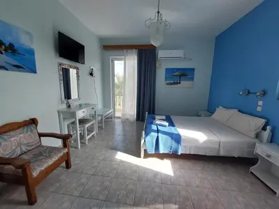 a bedroom with blue walls and a bed and a chair at Alexia Apartments & Studios in Kremasti