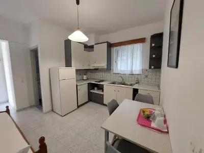 a kitchen with a table and a white refrigerator at Alexia Apartments & Studios in Kremasti