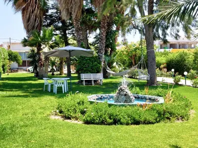 a fountain in a yard with a table and an umbrella at Alexia Apartments & Studios in Kremasti