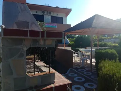 a patio with a stone fireplace and an umbrella at Kyriakos Studios in Afantou
