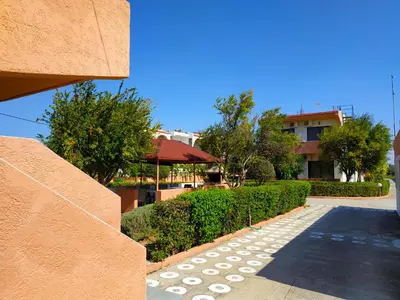 a walkway in front of a building with trees at Kyriakos Studios in Afantou