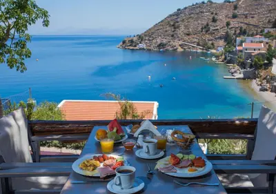 a table with food and a view of the ocean at Niriides Hotel Apartments in Symi
