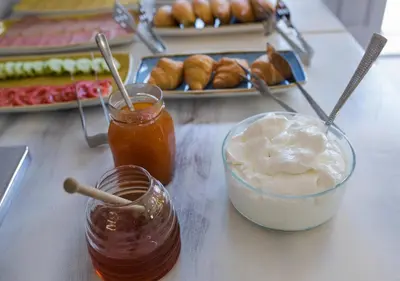 a table with two jars of honey and a plate of pastries at Niriides Hotel Apartments in Symi