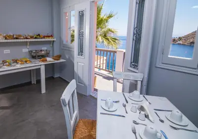 a kitchen with a table and a balcony with the ocean at Niriides Hotel Apartments in Symi