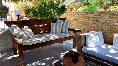 a wooden bench with pillows on a patio at Niriides Hotel Apartments in Symi