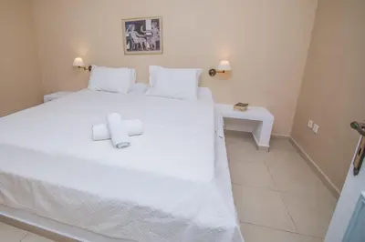 a bedroom with a white bed with two towels on it at Niriides Hotel Apartments in Symi